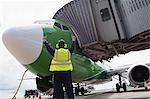 Rear view of airport ground crew worker directing airplane on runway