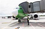 Airport ground crew worker standing next to airplane on runway