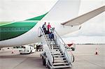 Passengers exit airplane down stairs at airport