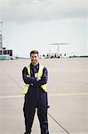 Portrait of airport ground crew standing with arms crossed on runway