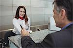 Airline check-in attendant handing passport to passenger at airport check-in counter