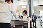 Airline check-in attendant handing passport to passenger at airport check-in counter