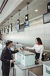 Businessman showing mobile boarding pass to airline check-in attendant at check-in counter