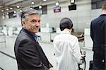 Business man waiting in queue at a check-in counter with luggage in airport terminal