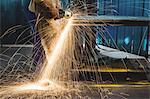 Mid-section of male welder working on a piece of metal in workshop