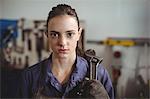 Female welder holding wrench tool in workshop