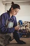 Female welder using digital tablet in workshop