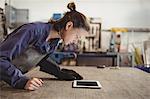 Female welder looking at digital tablet in workshop