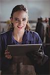 Portrait of female welder holding digital tablet in workshop