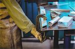 Mid-section of female welder using clamp tool in workshop