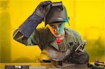 Female welder examining a piece of metal in workshop