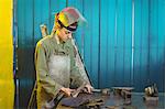 Female welder examining a piece of metal in workshop