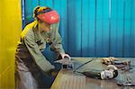 Female welder using a tool in workshop