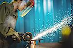 Female welder using circular saw in workshop