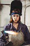 Female welder holding welding torch in workshop