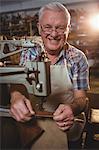 Portrait of shoemaker using sewing machine in workshop