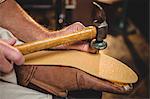 Shoemaker hammering on a shoe in workshop