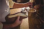 Shoemaker applying glue on shoe sole in workshop