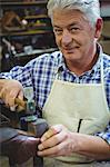 Portrait of shoemaker hammering on a shoe in workshop