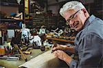 Portrait of shoemaker cutting a piece of material in workshop