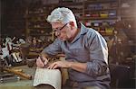 Shoemaker cutting a piece of material in workshop