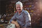 Portrait of smiling shoemaker sitting in workshop