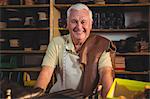 Portrait of smiling shoemaker sitting in workshop