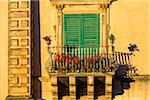 Detail of sunlit balcony and shuttered window in Ragusa in Sicily, Italy