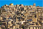 Rooftops of homes made of stone compacted on mountain side against a blue sky in historical Modica in the Province of Ragusa in Sicily, Italy