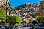 View of city street with homes on mountain side in historical Modica in the Province of Ragusa in Sicily, Italy