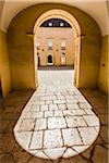 Sunlit archway and stone courtyard at Donnafugata Castle in historic Ragusa in the Province of Ragusa in Sicily, Italy