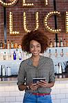 Portrait of happy young woman with a digital tablet at bar counter