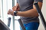 Midsection view of a man using smart watch in a gym