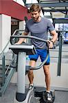 Man exercising legs using a resistance weight machine in the gym
