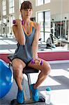 Young woman exercising with dumbbells in a fitness club