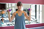 Beautiful happy woman exercising with dumbbells in a gym