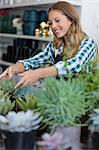 Happy woman arranging plants in her shop