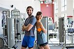 Young couple standing back to back in a fitness club
