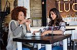 Female friends taking a picture of coffee cup with smartphone at cafe