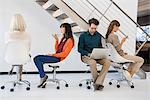 Business executives sitting on chairs busy in different activities