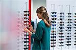 Young woman shopping for sunglasses in optical shop