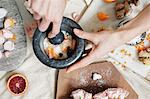 A woman's hand using a pestle and mortar on a kitchen counter.