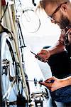 A bike mechanic in a bicycle repair shop using a smart phone.