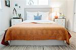 A bedroom in an apartment with a double bed and a retro look antique patterned patchworked bed cover.