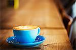 Specialist coffee shop. A blue china cup and saucer with frothy coffee.