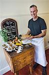 Cafe owner with fresh pie and muffins on display table