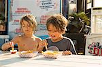 Two young boys eating fast food beside fast food trailer