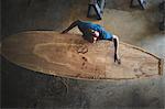 Craftsman making paddleboard in workshop, overhead view