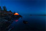 Illuminated tent on rocky coast