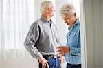 Mature adult couple standing having a drink in a room.